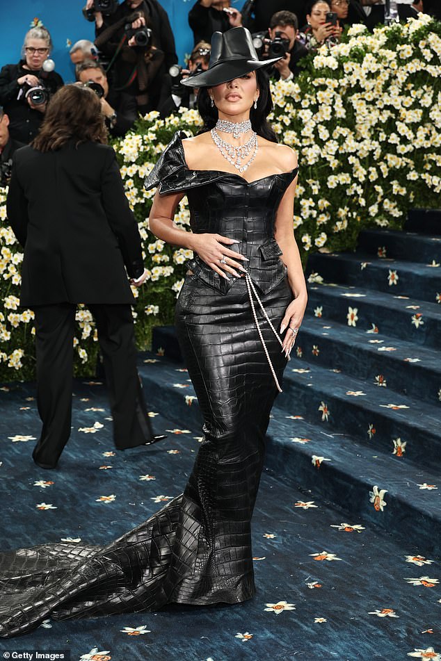 After a slight red carpet mishap، Kim Kardashian، 44، wowed in a Chrome Hearts black snakeskin corset with matching skintight skirt، flashing her ample cleavage and her toned back