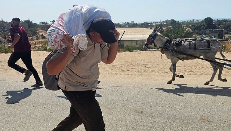 نازحون فلسطينيون يسيرون على طريق لاستلام مساعدات إنسانية من مؤسسة تدعمها أمريكا 